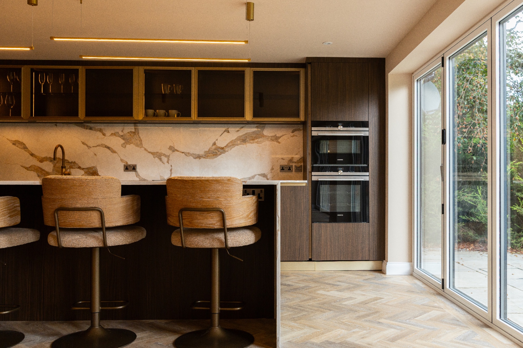 AY Group bespoke kitchen with timber cabinetry, marble surfaces and garden-facing glazing